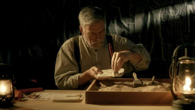 A scene from the 1800s of a mature Egyptologist carefully cleaning a piece of pottery with the Eye of Ra engraved on it.