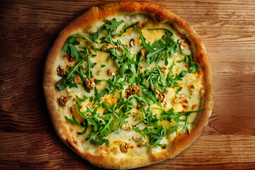 Delicious vegeterian cheese pizza with walnuts and basil wooden table background, closeup