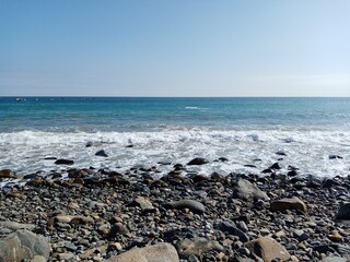 Fototapeta na wymiar Vista de playa con piedras, rocas y olas