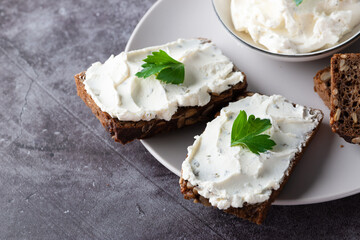 Rye bread with cream cheese on grey table. Whole grain rye bread with seeds