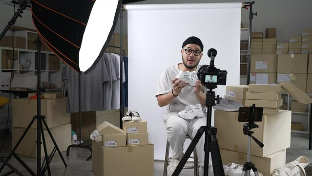 Young attractive Asian man blogger or vlogger looking at camera reviewing product and merchandise. Business online influencer on social media concept.