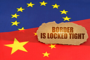 On the flags of China and the European Union lies a cardboard plate with the inscription - Border is locked tight