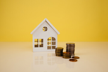 House model and coin on yellow background. Saving money for buy a new house concept