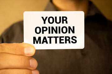 Closeup on businessman holding a card with text YOUR OPINION MATTERS, business concept image.