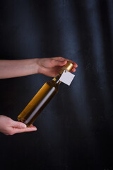 Hands holding bottle of white wine with template label, no brand. Riesling, chardonnay, sauvignon blanc. Alcohol beverage on black background