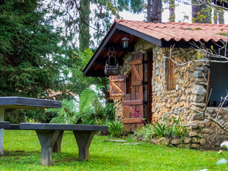 Monte Verde, Minas Gerais, Brasil - April 22 2022: traditional stone housing with wooden window and doors, and a picnic table on the grass