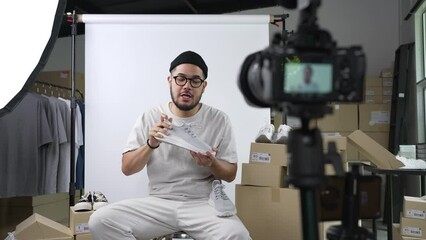 Young attractive Asian man blogger or vlogger looking at camera reviewing product and merchandise. Business online influencer on social media concept.