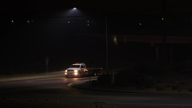 Tow truck entering freeway onramp on a dark night. Low visibility and headlight beams showing in the smoke from wildfires