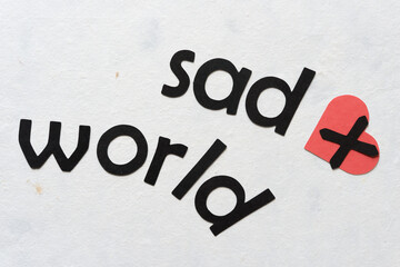 letters on paper - "sad world" and red paper heart with letter X