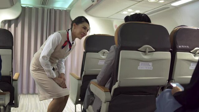 The female cabin crew was smiling and serving passengers on the flight she was willingly serving. The businessman passenger called the crew for service during the flight in travel concept.