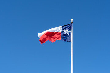 Flag of Texas waving in the wind with blue sky in the background. 
Texas is a state in the South Central region of the United States.
