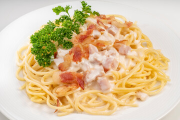 Spaghetti carbonara with Crispy Bacon and Ham on white plate on white background, Carbonara pasta with parmesan cheese and cream sauce, Traditional italian cuisine.
