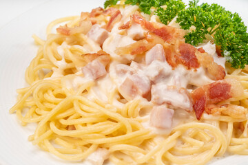 Spaghetti carbonara with Crispy Bacon and Ham on white plate on white background, Carbonara pasta with parmesan cheese and cream sauce, Traditional italian cuisine.