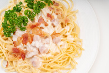 Spaghetti carbonara with Crispy Bacon and Ham on white plate on white background, Carbonara pasta with parmesan cheese and cream sauce, Traditional italian cuisine.
