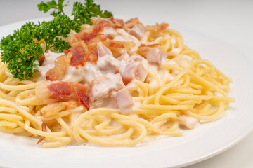 Spaghetti carbonara with Crispy Bacon and Ham on white plate on white background, Carbonara pasta with parmesan cheese and cream sauce, Traditional italian cuisine.