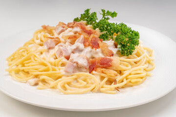 Spaghetti carbonara with Crispy Bacon and Ham on white plate on white background, Carbonara pasta with parmesan cheese and cream sauce, Traditional italian cuisine.