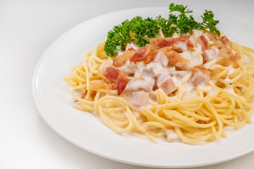 Spaghetti carbonara with Crispy Bacon and Ham on white plate on white background, Carbonara pasta with parmesan cheese and cream sauce, Traditional italian cuisine.