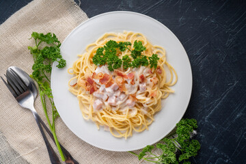 Spaghetti carbonara with Crispy Bacon and Ham on white plate on black background, Carbonara pasta with parmesan cheese and cream sauce, Traditional italian cuisine.cuisine.