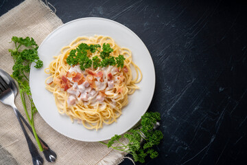 Spaghetti carbonara with Crispy Bacon and Ham on white plate on black background, Carbonara pasta with parmesan cheese and cream sauce, Traditional italian cuisine.cuisine.