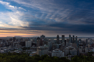 Panorama of the Montreal skyline at dawn during a warm summer morning, skyscrapers, orange and blue sky before sunrise with grey cirrus clouds, seen from the Kondiaronk belvedere