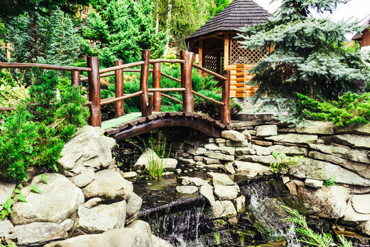Photo of exterior designed forest short river or stream bridge with wooden garden pavilion.