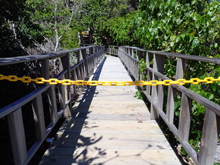Fototapeta na wymiar Wooden footbridge blocked by yellow chain