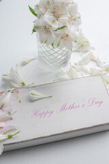 Wooden frame with the inscription "Happy Mother's Day" and delicate white flowers on a light background.
