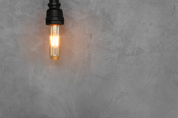 Light on empty loft gray background or old incandescent lamp with warm white for business idea and vision solution on wall, vintage light bulb, creativity of new ideas, interior decor with copy space