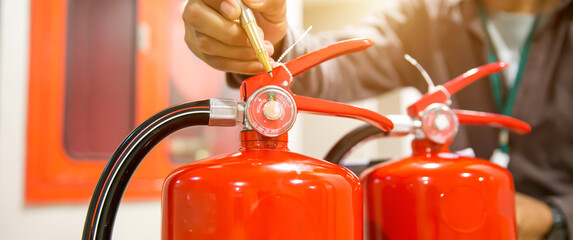 Fire extinguisher has hand engineer inspection checking pressure gauges to prepare fire equipment for protection and prevent emergency and safety rescue and alarm system training concept.