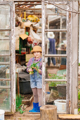 a funny little girl in a hat with green onions in the greenhouse 