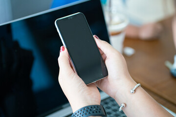 Business women hand use smartphone with laptop sitting in office