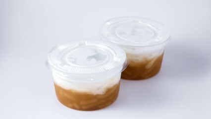 Sweet Rice Noodles with Coconut Cream in a plastic cup on a white table.