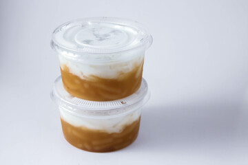 Sweet Rice Noodles with Coconut Cream in a plastic cup on a white table.