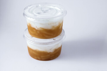 Sweet Rice Noodles with Coconut Cream in a plastic cup on a white table.