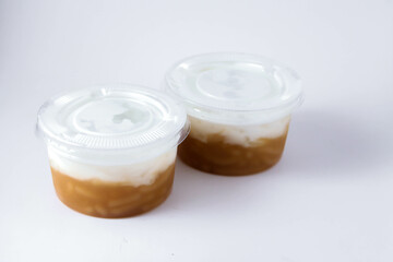 Sweet Rice Noodles with Coconut Cream in a plastic cup on a white table.