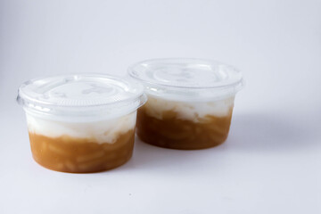 Sweet Rice Noodles with Coconut Cream in a plastic cup on a white table.