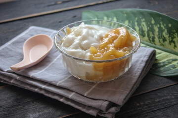 Sweet Rice Noodles with Coconut Cream served in a glass cup on a black wooden table.