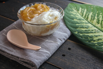 Sweet Rice Noodles with Coconut Cream served in a glass cup on a black wooden table.