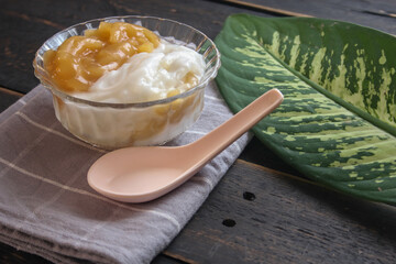 Sweet Rice Noodles with Coconut Cream served in a glass cup on a black wooden table.