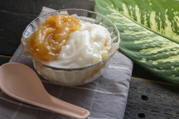 Sweet Rice Noodles with Coconut Cream served in a glass cup on a black wooden table.