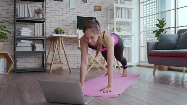 Fit young woman practicing yoga at home via online class with professional instructor, sport and healthy lifestyle concept.