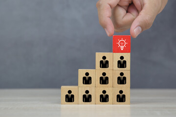 Hand choose cube wooden block stack with lightbulb on human icon stack in pyramid for leadership and business team creative thinking and human resources for teamwork or team player.