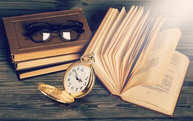 Antique pocket watch on opened old book on background.