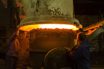 Metallurgists working at an industrial furnace