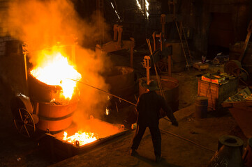 Metallurgist removing slack from hot molten metal