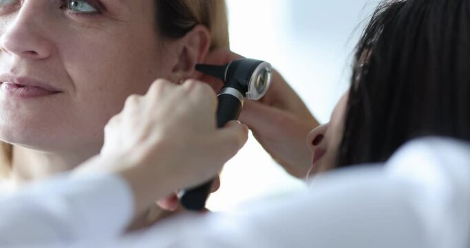 ENT conducts medical examination of ear to woman