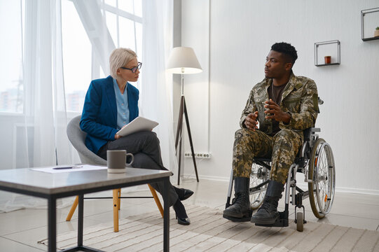 Paraplegic soldier in wheelchair talking with therapist