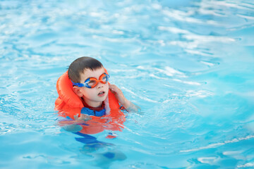 little boy learn to swim in the pool