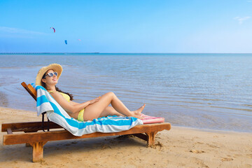 young woman in straw hat and sunglasses relaxing on sun lounger