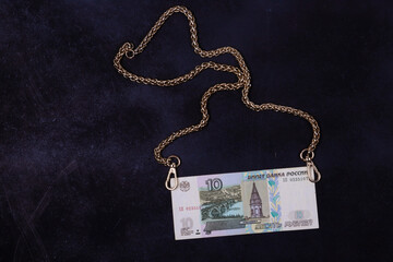 Fototapeta na wymiar a ruble and a gold chain on a black and blue background